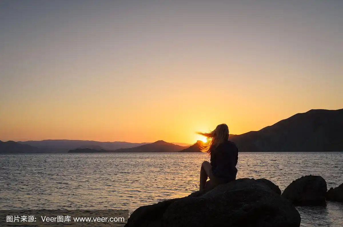 一个女孩的剪影在日落的背景在海边
