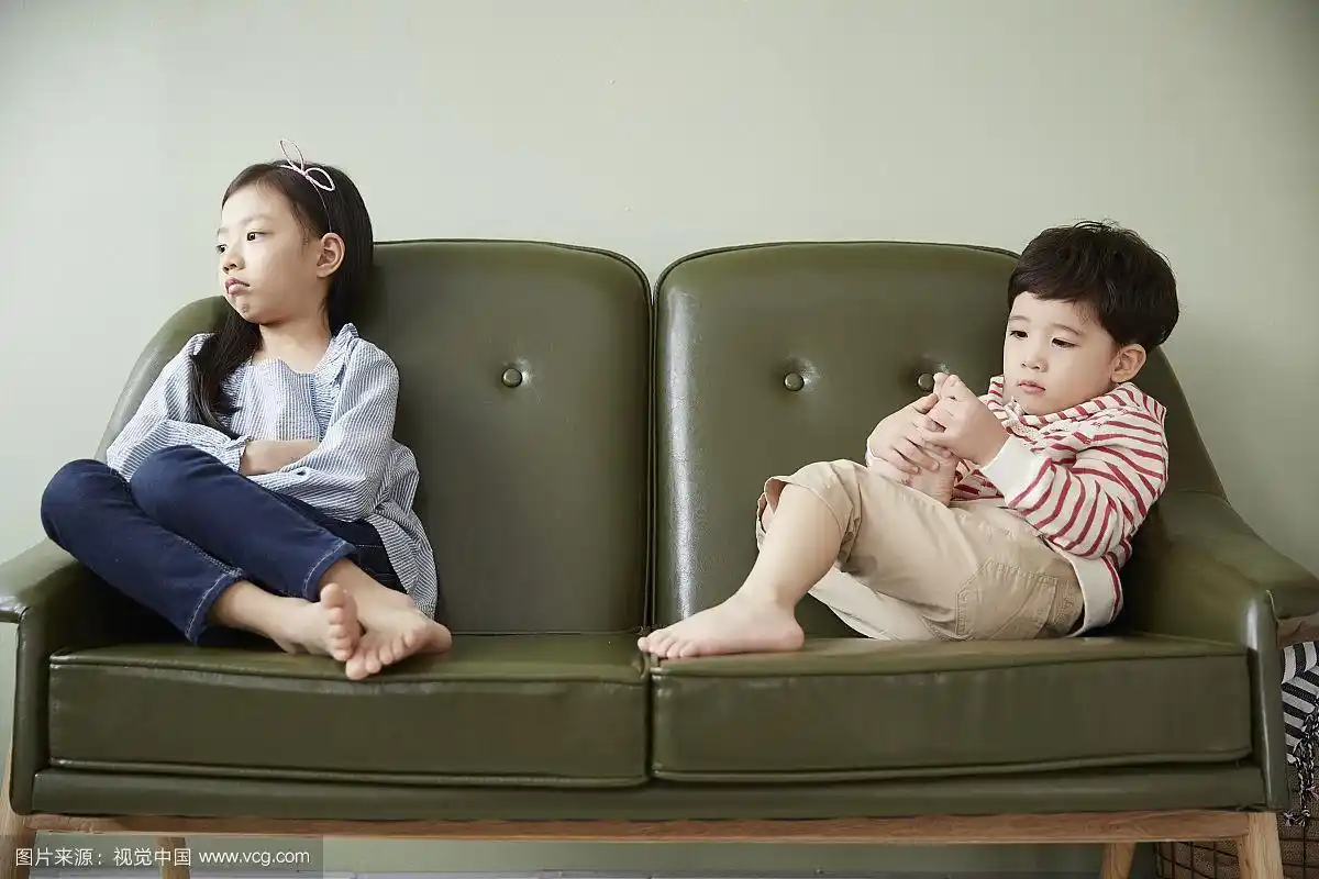 小男孩和小女孩面对面坐在沙发上的照片