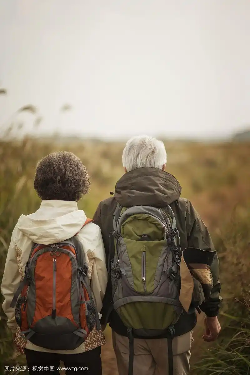 一对老年夫妇在济州岛的银草上牵手徒步旅行的照片