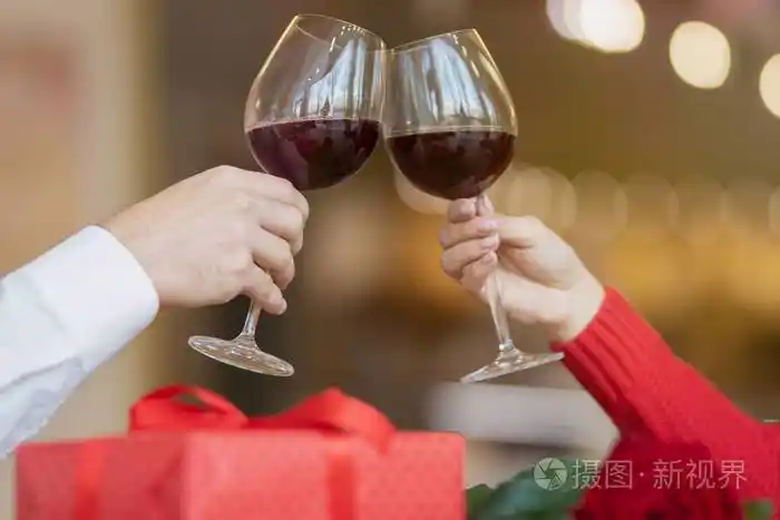 桌上有一个礼品盒和一朵美丽的玫瑰.一男一女在咖啡馆喝酒.