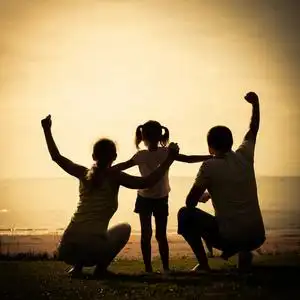 幸福的家庭站在海滩上在日出的时候照片