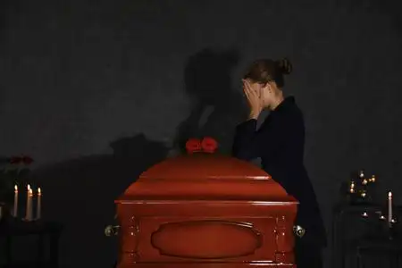 一位悲伤的年轻女子在小教堂里用红玫瑰在灵柩旁哀悼照片