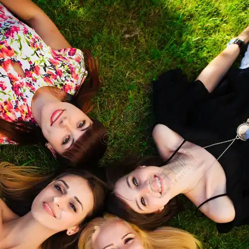 四个漂亮的年轻姑娘在公园的背景下摆姿势