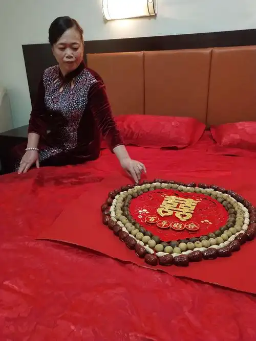 清晨4点毋亲亲手为一对新人铺被,并将寓意为早生贵子百年好合的吉祥物