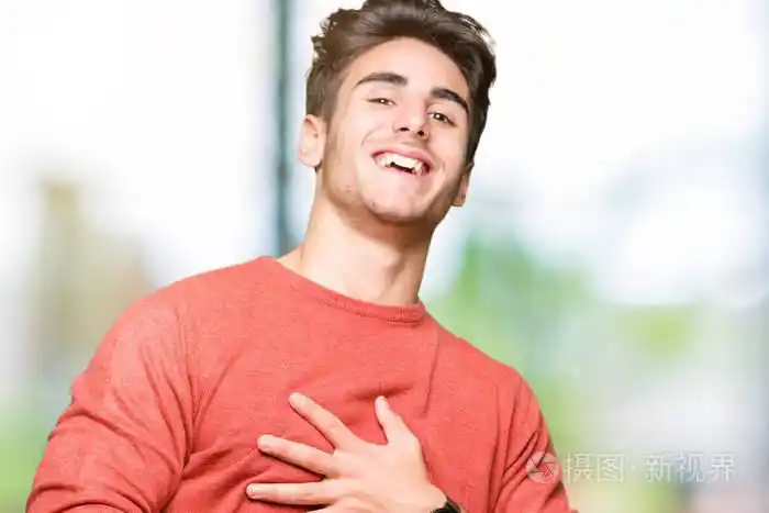 年轻的英俊男子越过孤立的背景微笑和大笑大声,因为有趣的疯狂笑话.