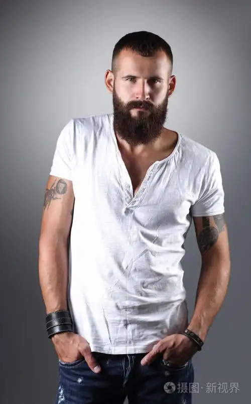 英俊的大胡子男人站,灰色的背景上孤立的肖像