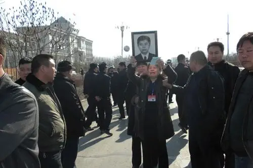 陈国君家属手持陈国君遗像站在法院门外