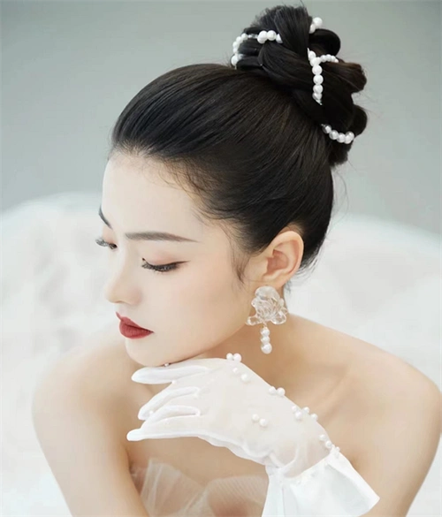 饱满圆润的花苞盘发,一圈的珍珠搭配,打造出高贵优雅的赫本风发型.