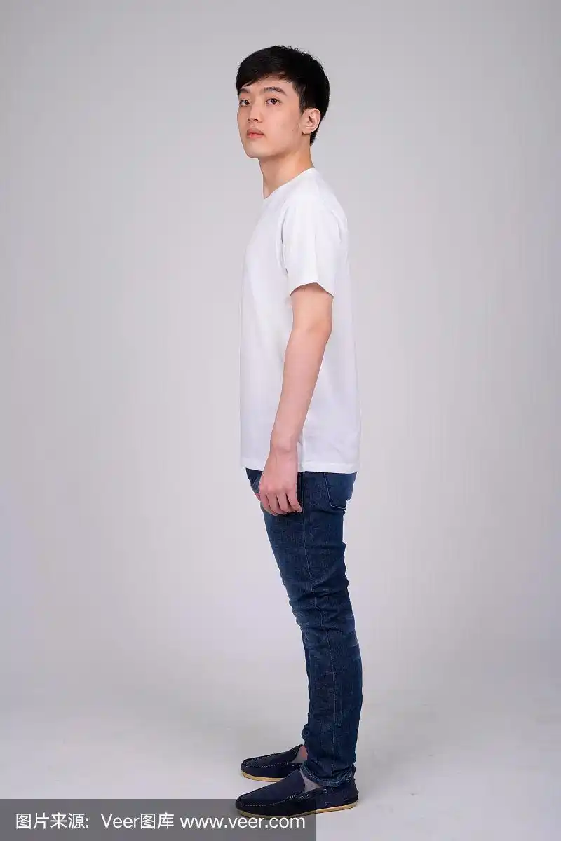 全身拍摄的侧面视图,年轻的亚洲男子看着相机