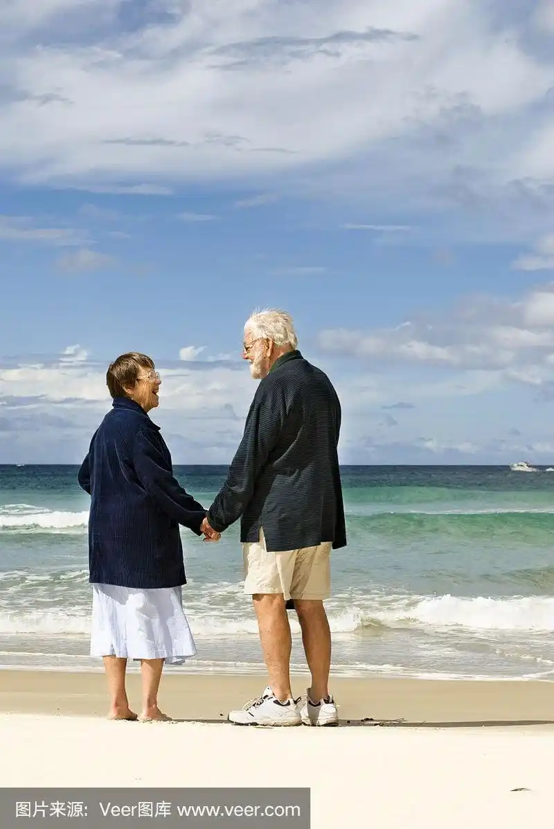 一对深情的老年夫妇在海滩上牵着手