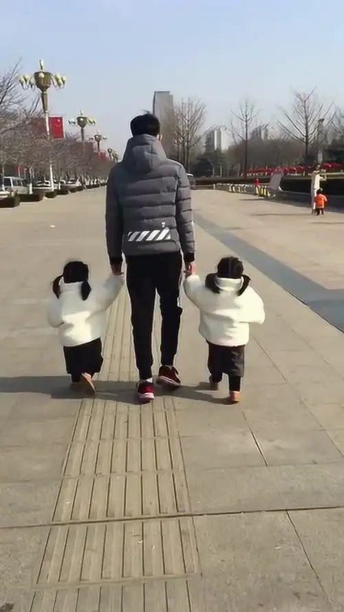 相差14岁的兄妹,哥哥拉着妹妹的手,广场休闲走一走!