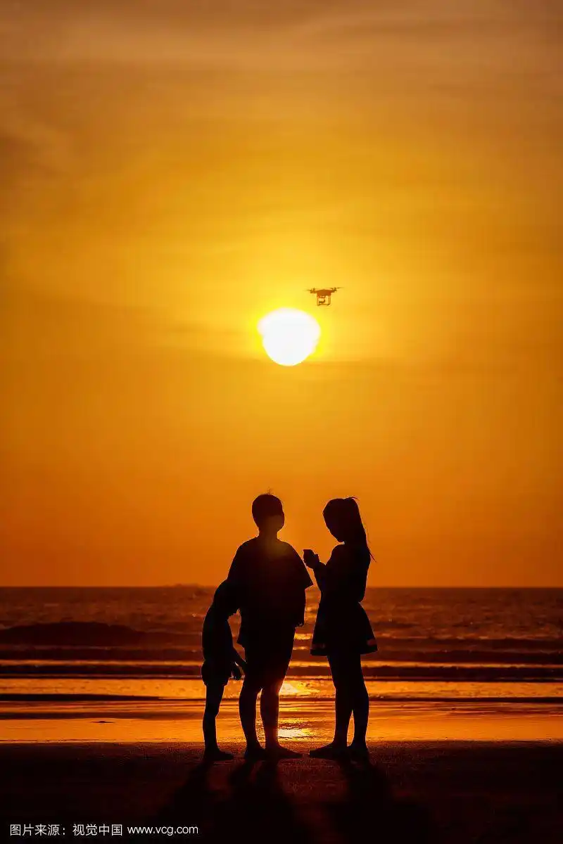 海岸边逆光站立的一家三口