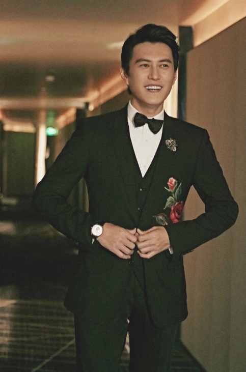 靳东气质率性的发型,白衬衫黑领带身穿黑色刺绣西服套装,下身一双黑