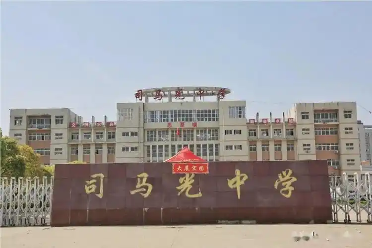 在司马光中学,同学们在校门口间隔一米排队,工作人员对学生与行李消杀