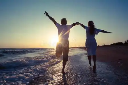 情侣一起奔跑快乐的情侣在沙滩上奔跑照片