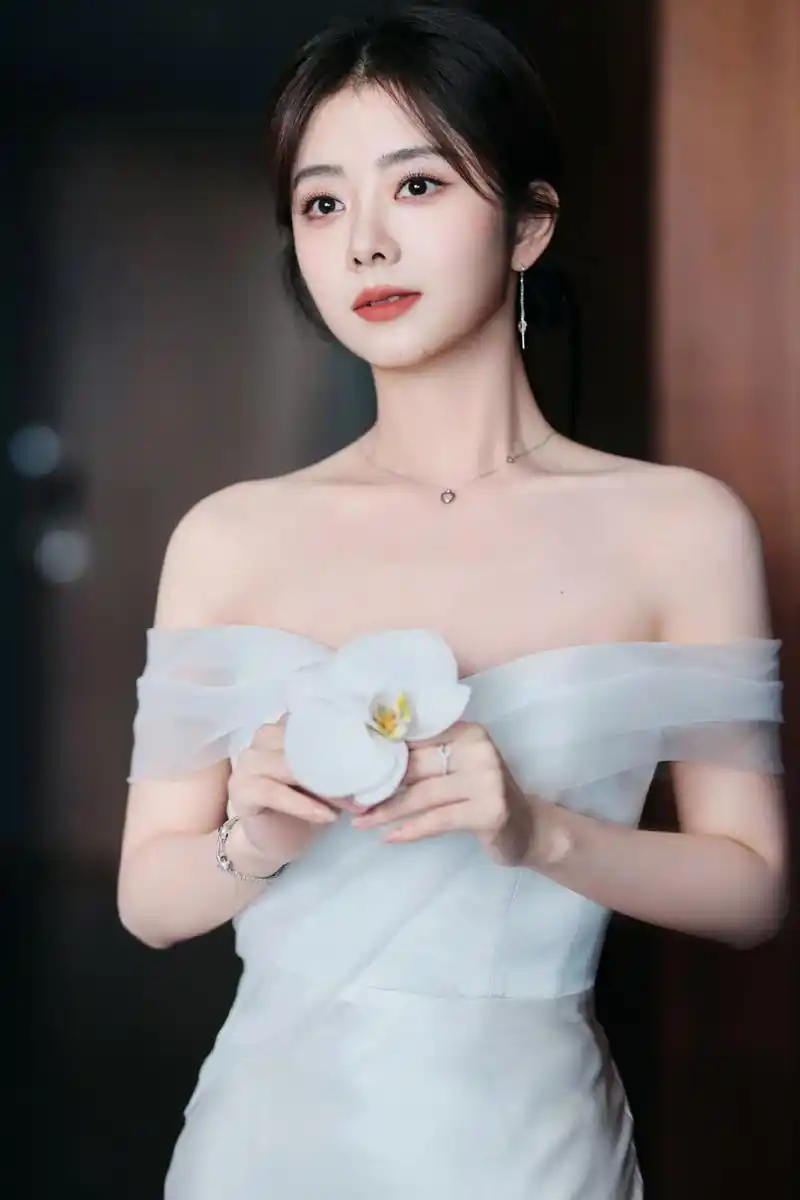 谭松韵纯白丝绸长裙露肩 手捧白花纯洁优雅 7月8日,谭松韵工作室晒出