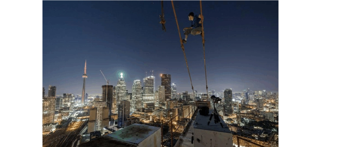 瑞亚博伊(tom ryaboi )站在连接摩天大楼的两根电缆上.