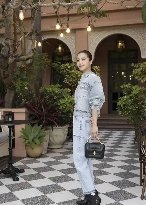 蔡依林选择了一款露脐白色t恤和高腰牛仔裤的搭配,看起来既凸显身材