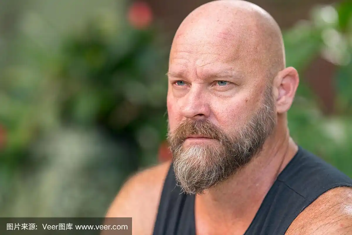 一个英俊的光头男子的特写镜头,胡子看着远离相机