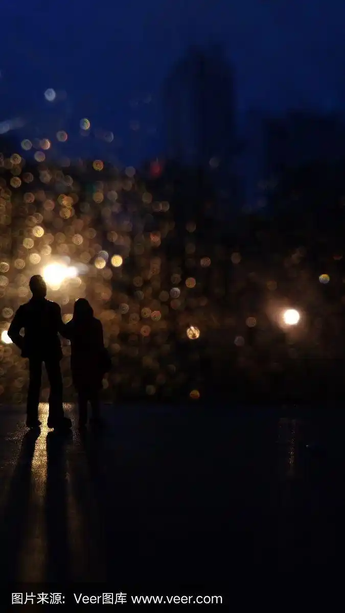 小情侣剪影在雨夜欣赏灯光