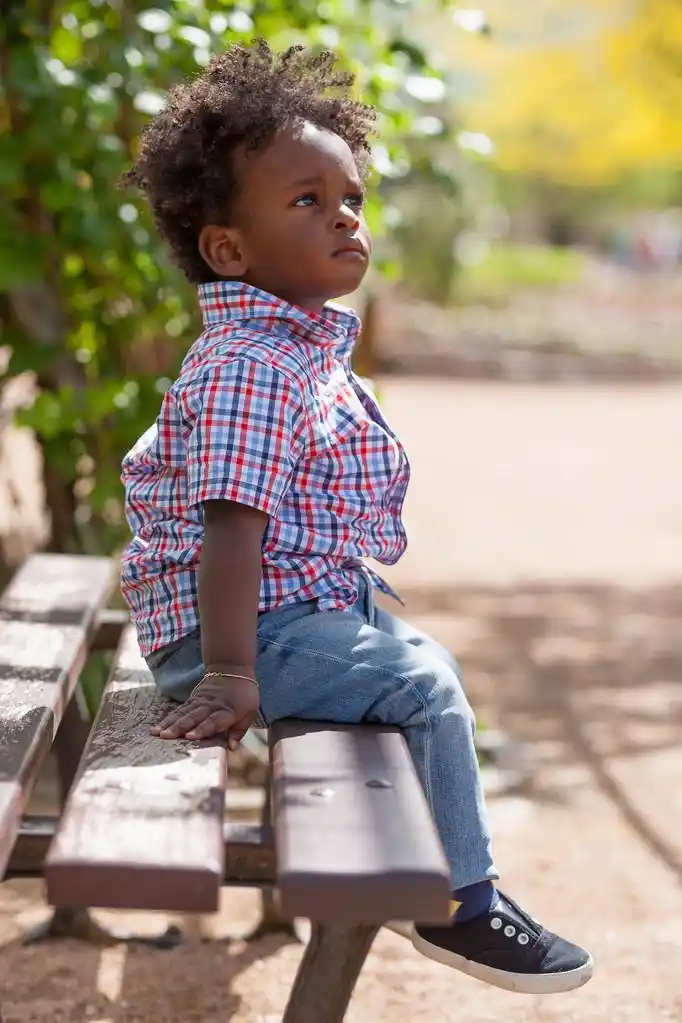 座落在一条长凳上黑人小孩的室外肖像