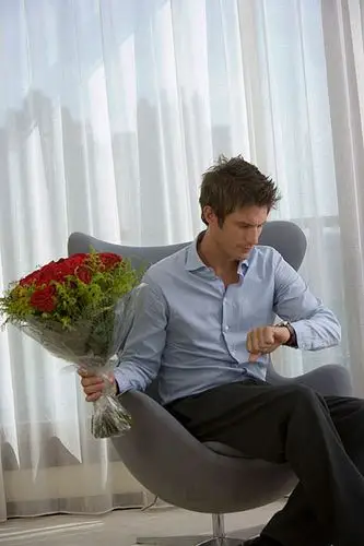 一位手捧鲜花坐在椅子上等人的先生