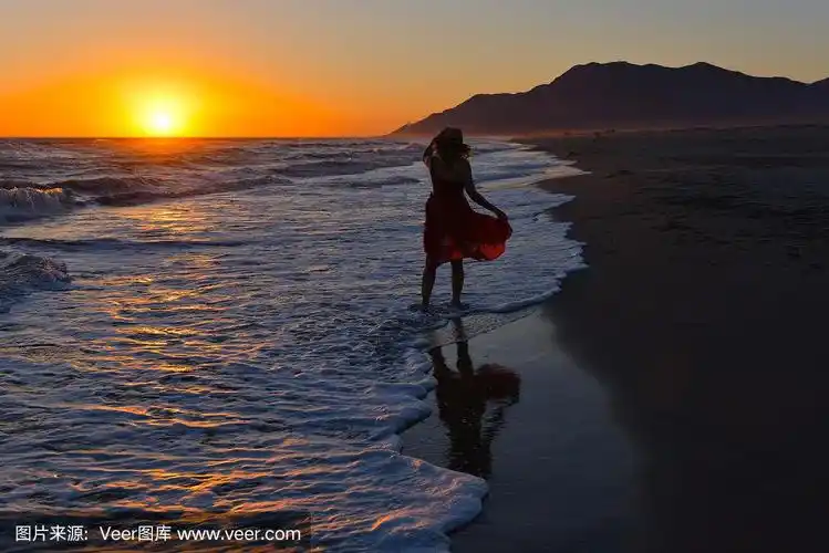 日落时分,一个女人在海滩上散步.