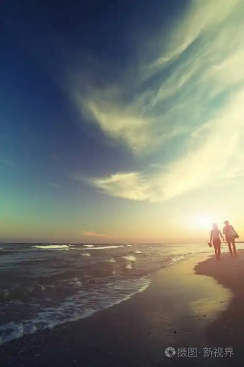 两个年轻的女孩在日落时分在海边漫步