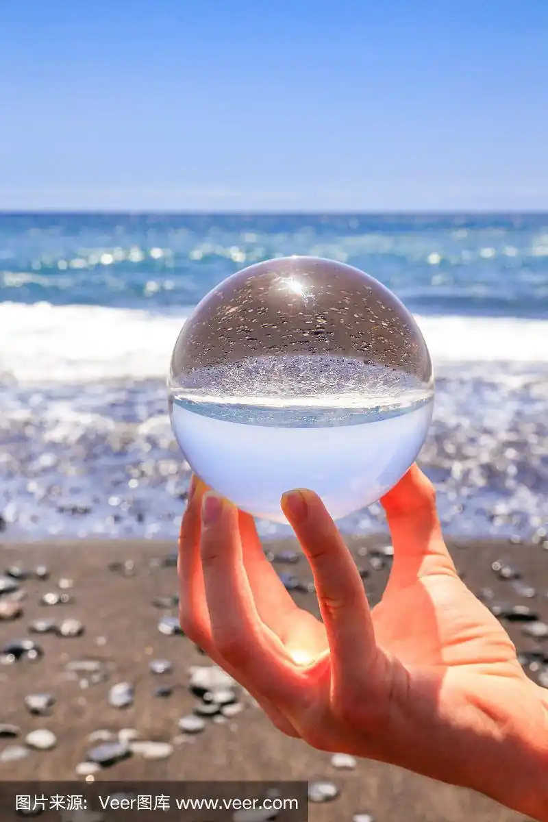 手握玻璃球在海滩和海边