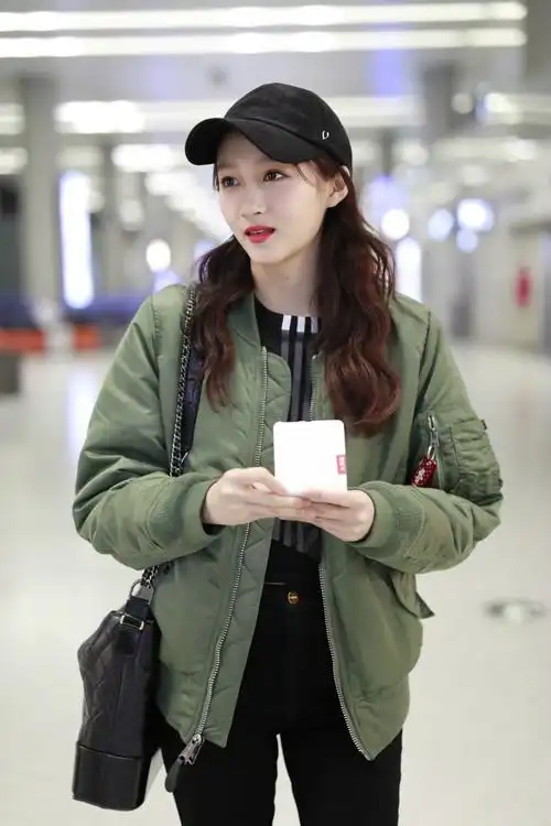关晓彤红唇穿军绿色外套搭配黑裤现身机场,戴黑色棒球帽皮肤白皙