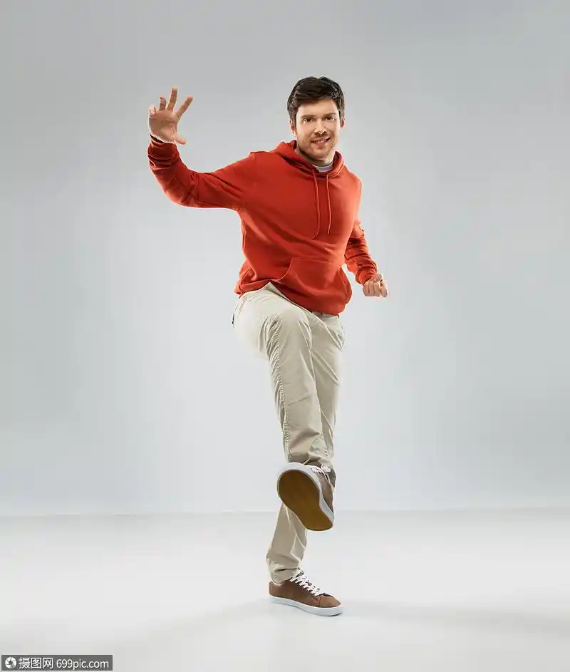 动作人的微笑的轻人穿着红色帽衫,站灰色的背景上穿着帽衫的快乐轻人