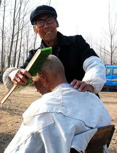 理发匠一个挑子把全部家什担来,给过年的农民剃光头,刮胡子.