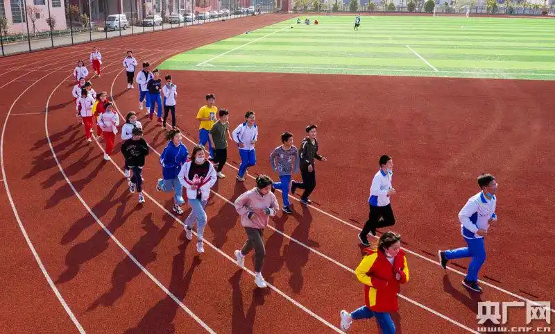 在体育课上,学生们迎着春光跑步锻炼,校园里重现生机勃勃的景象.