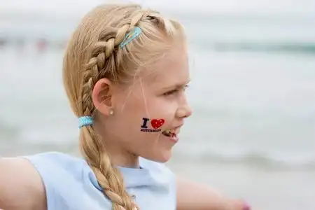 可爱的白种金发女孩,脸上临时纹着"我爱澳大利亚",在海边庆祝澳大利亚
