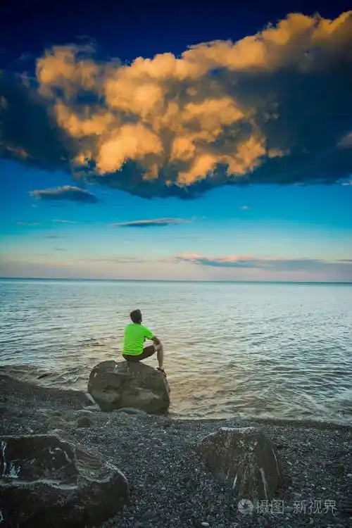 坐在海边的一块石头上的男人
