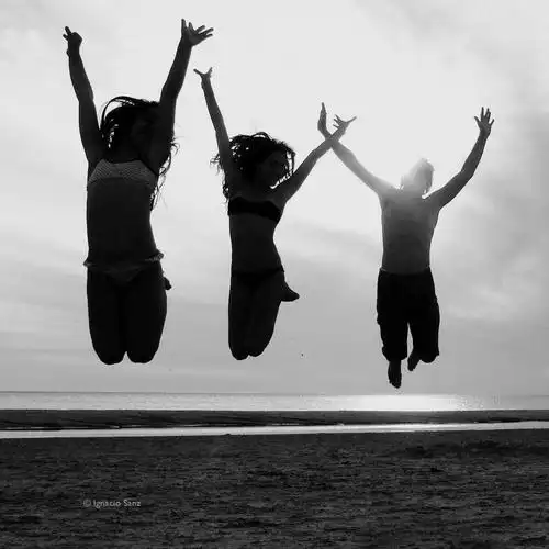 在白天高清壁纸在多云的天空下跳跃的三人剪影