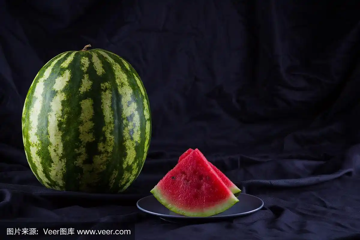 黑布上的西瓜.黑色背景下的整个西瓜.素食主义者的健康食品.本空间