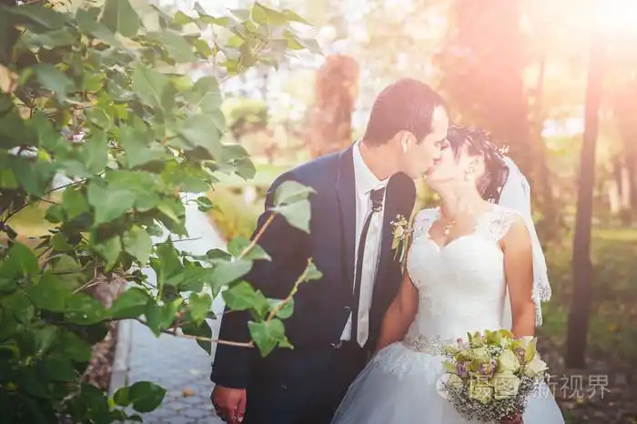 照片 接吻的结婚礼服的年轻夫妇.新娘控股束鲜花.jpg