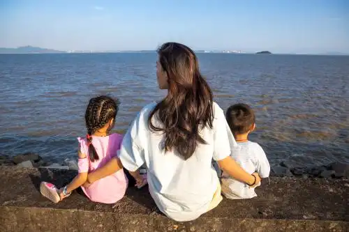妈妈带着两个孩子在堤岸上看大海
