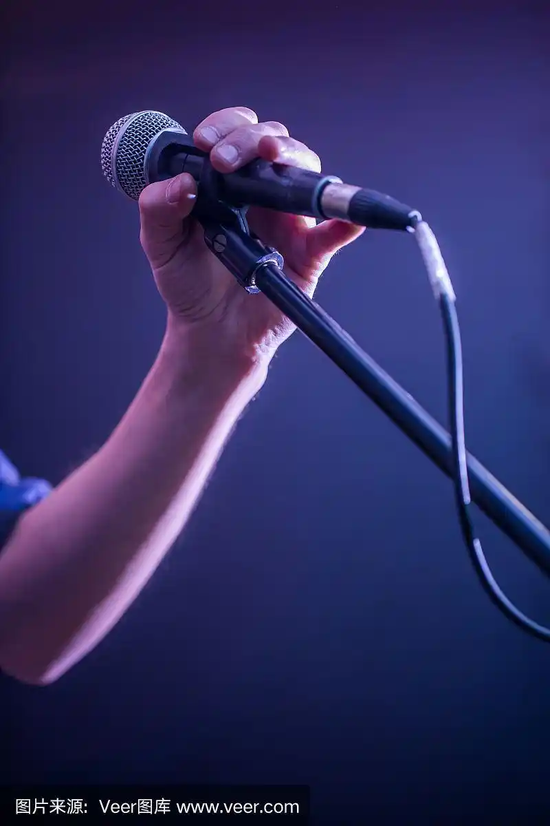 手拿麦克风放在黑色背景上,音乐概念,美丽的舞台灯光