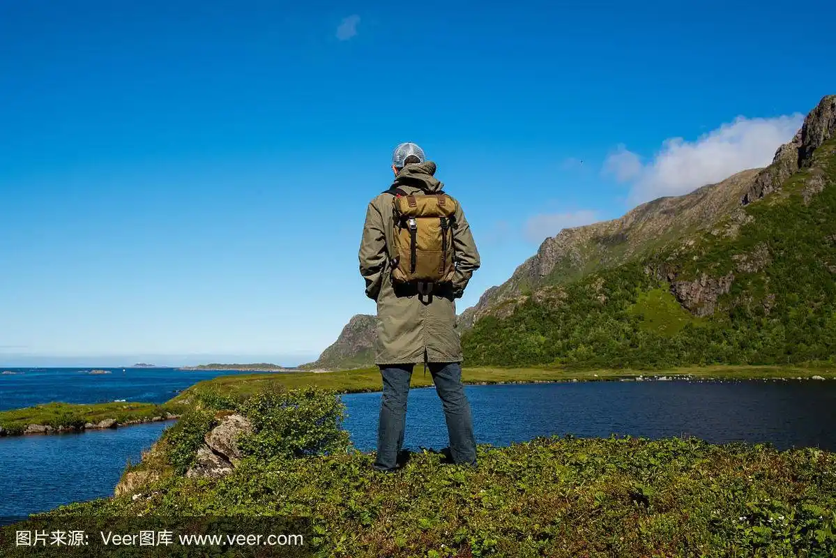 一个背着双肩包的男人享受着山与海的美妙风景.风景优美的观点.