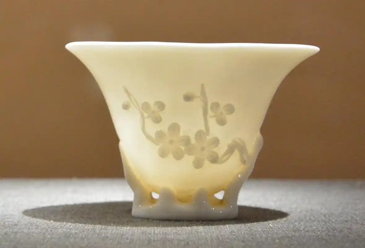 明 德化窑白釉堆贴梅花纹椭形杯在制作技艺上,德化白瓷突出原材料的