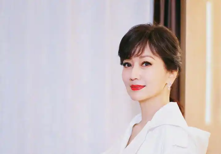 照片中的赵雅芝身穿一身白衣,腰间系有蓝色腰带,涂上红唇格外显气 ..