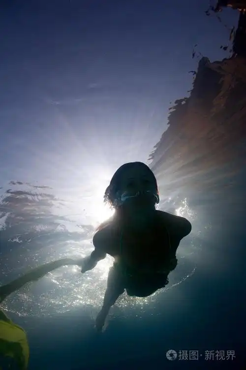 女人剪影水下在游泳池与背光源