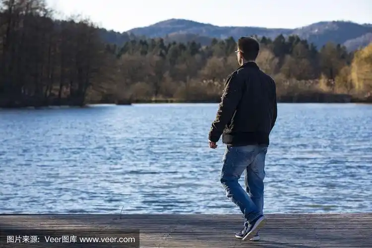 一个年轻的成年人在卢布尔雅那公园的一个小湖边散步