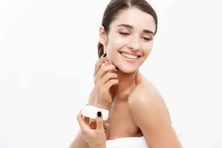 美容青年护肤概念-关闭美丽的白种女人脸肖像涂抹一些奶油她的脸.