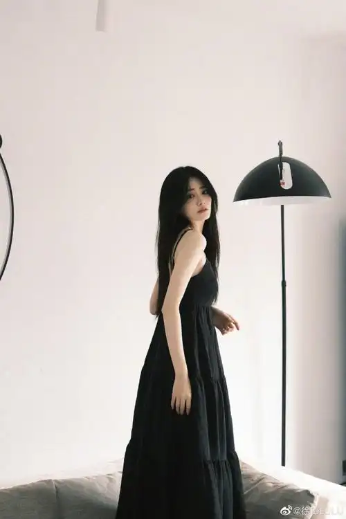 徐璐在个人社交平台晒出一组黑色连衣裙造型随拍,她披散长发在沙发上