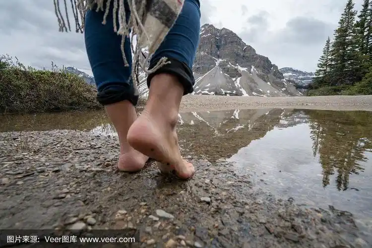 年轻女子赤脚在湖边散步