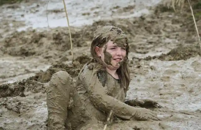 一个女孩侧躺在泥浆里,满身都是泥巴,毫不嫌弃(图片来自东方ic)