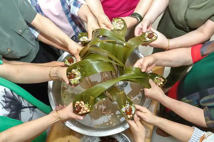 在包粽子现场,有经验的职工当起了"师傅",不会包的职工虚心请教,大家